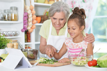 grandmother and granddaughter preparing dinner 