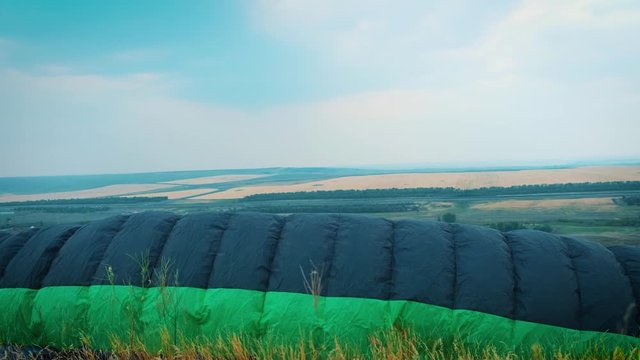 hang glider flying over a field. The wing of the paraglider lies on the ground in the steppe. Soon they will take off. Feeling of freedom and a sense of flying. The beginning of adventure. Paraplane.
