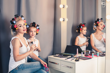 Mother and her child girl are doing your makeup and having fun