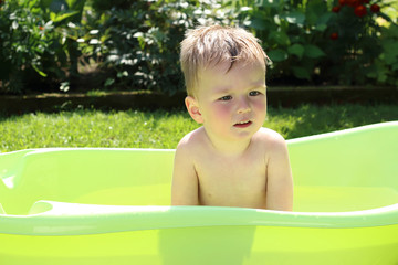 The boy bathes in the garden on a Sunny day
