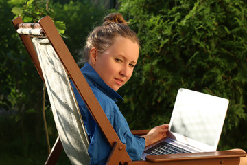 Young woman working with laptop outdoors, sitting on sunbed