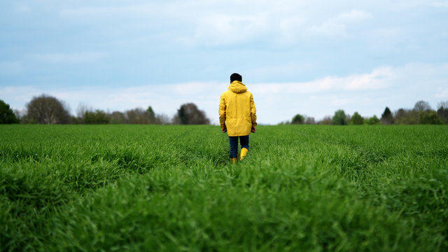 man in yellow raincoat in field