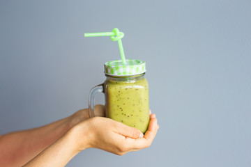 Healthy green smoothie in woman's hand. Vegan, raw food, detox and diet lifestyle.