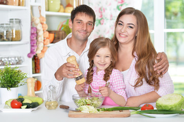 parents with daughter preparing dinner 
