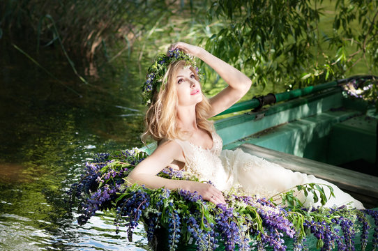 Portrait Of Slavic Or Baltic Woman With Wreath Sitting In Boat With Flowers. Summer