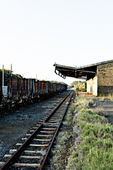 Fototapeta na wymiar Old, rusty freight train alongside abandoned railway station.