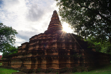 Archaeological site, ancient abandoned temple and pagoda in Thailand with sun flare.