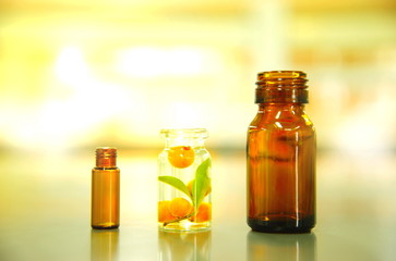 brown glass bottle and vial and clear glass with orange fruit and green leaf in alternative medical science laboratory background