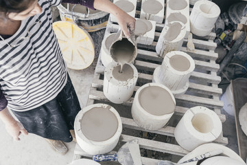 Woman artist poring ceramic slip into a casting mould