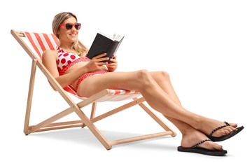 Young woman reading a book in a deck chair