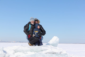 Fototapeta na wymiar Happy family sitting on an ice floe on a frozen river in winter, Ob River, Russia
