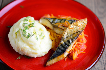 Fried fish with mashed potatoes  on a red round plate.Homemade food on a wooden table, brown background. A simple concept of healthy food.