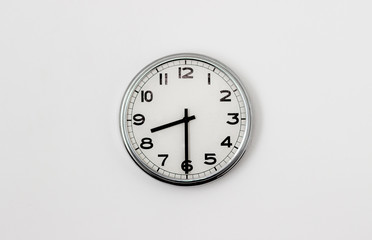 White Clock hanging on a white wall showing time 8:30