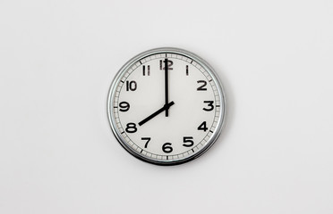 White Clock hanging on a white wall showing time 8:00