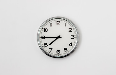 White Clock hanging on a white wall showing time 7:45