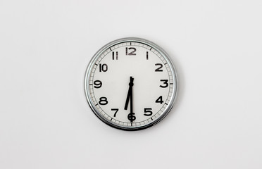 White Clock hanging on a white wall showing time 6:30