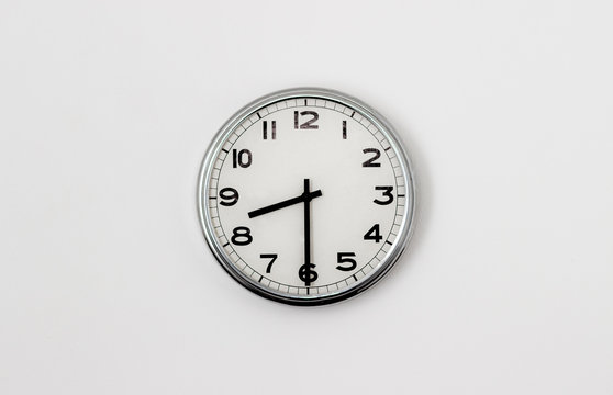 White Clock hanging on a white wall showing time 8:30