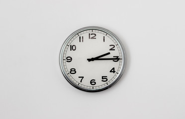 White Clock hanging on a white wall showing time 2:15