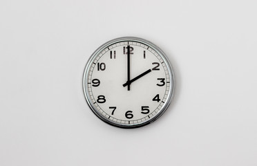 White Clock hanging on a white wall showing time 2:00