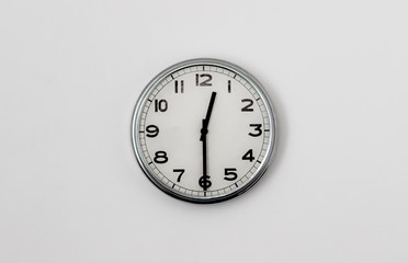 White Clock hanging on a white wall showing time 12:30