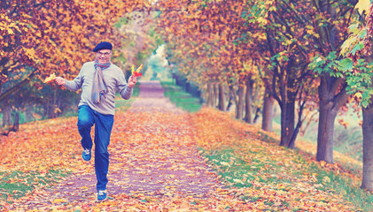 aktiver Senior springt im Herbst freudig durch den Park