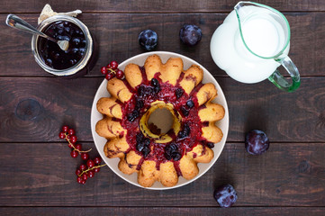 Large freshly baked cake with summer berries on a dark wooden table.