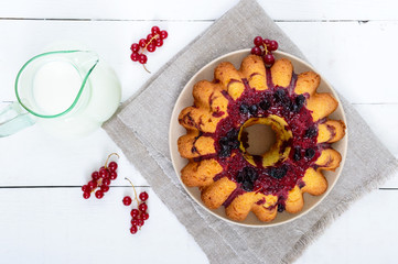 Freshly baked cake with summer berries, jug of milk on a white background. Top view.