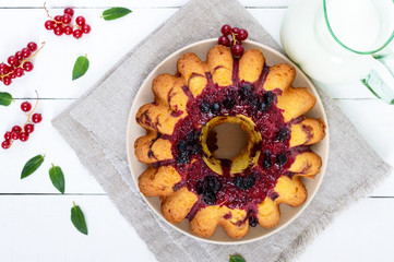 Freshly baked cake with summer berries, jug of milk on a white background. Top view.