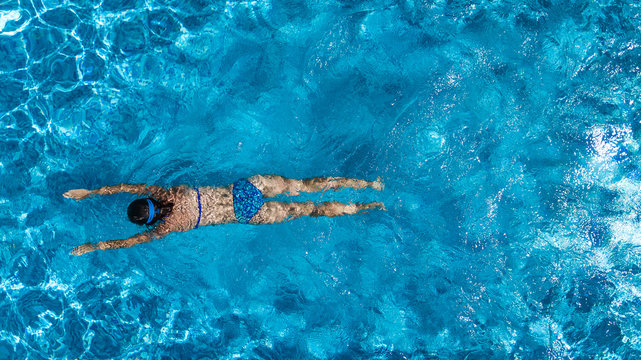 Aerial top view of woman in swimming pool water from above, tropical vacation holiday concept
