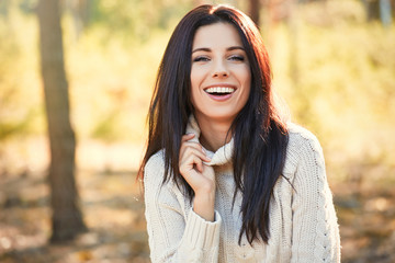 Portrait of a beautiful smiling woman in the autumn forest. Welcome warm autumn. Cute girl on a golden autumn background.