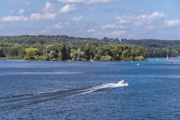 Obraz premium Schnelles Motorboot rast am Starnberger See vorbei an der Roseninsel