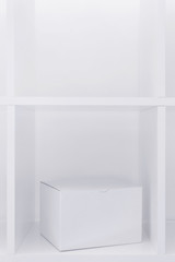 White cardboard box on wooden shelf as copy space