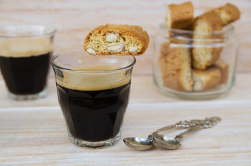 Two cups of black coffee with foam and Italian biscotti cantuccini on wooden table. Italian almond sweets biscuits (cookies) background.