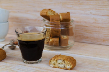 Glass of black coffee with foam and Italian biscotti cantuccini on wooden table.Italian almond sweets biscuits (cookies) background with copy space.