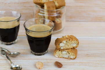 Two cups of black coffee with foam and Italian biscotti cantuccini on wooden table.Italian almond sweets biscuits (cookies) background with copy space.