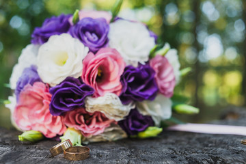 wedding rings and bouquet on the wooden surface