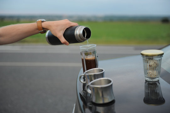Alternative brewing coffee in a french press on the hood of a car on the side of the road on a journey