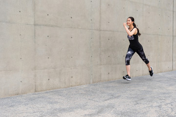 Fototapeta premium young female jogger jogging on gray background