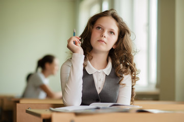 schoolgirl eager to answer a question,Girl holding pencil looking up