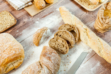 Naklejka premium Fresh bread slice and cutting knife on rustic wooden table