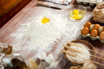 Egg yolk in flour on a wooden table in a bakery. Rural or rustic style.