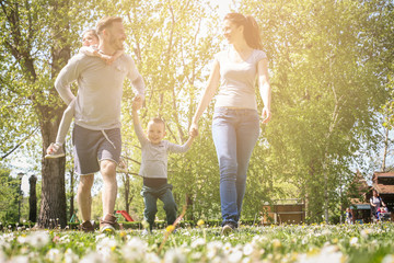 Happy parents playing with their children in the meadow. Happy family walking together in the meadow.