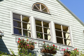 Fototapeta na wymiar Wood house windows with flowers under them.