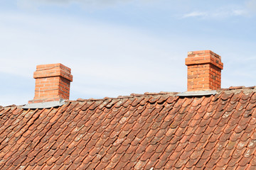 Countryside view of two small chimneys on rooftop.