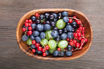 Red black currant blueberry gooseberry in a wooden bowl