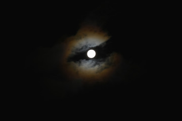 不思議な光景・雲間から見える月「空想・雲のモンスター〔モンスターの巨大な目（月が目）がこちらを見つめているイメージ〕」不思議な眼光、神秘的な眼差し、すべてを見通す力、じっと見る、猫目、幽霊のような、怖い、未来などのイメージ
