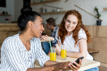 multiethnic girls with smartphone and juice