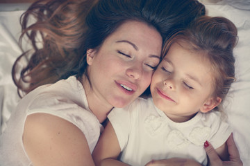 Young mother playing with her little daughter on bed. Enjoy together in free time.