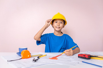 Asian girl child playing as an engineer the building layout and helmet are smiling and happy on weekends.