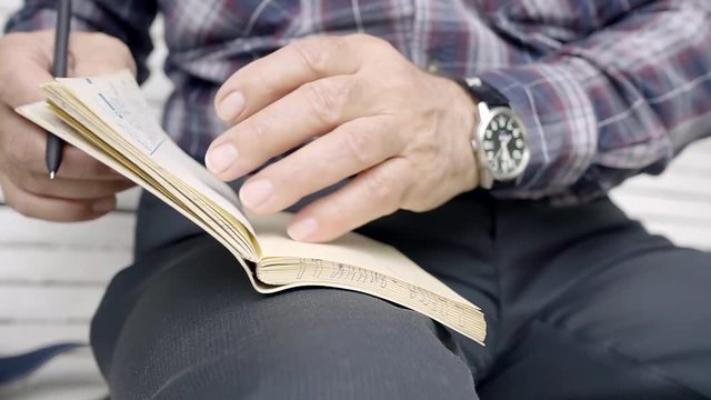 close-up. hands of an elderly man flipping through the pages of the old notebook and pen in recording